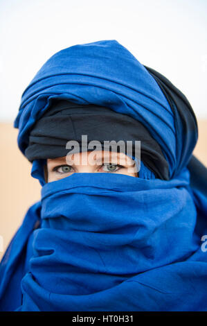 Una donna con gli occhi blu che indossa un headscalf blu nel deserto del Sahara, Marocco Foto Stock