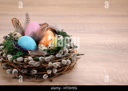 Decorazioni per la Pasqua. Bird's Nest con moss rivestita con piume, uova colorate e i rami di salici Foto Stock
