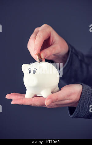 Donna mettendo una moneta in euro nel salvadanaio, risparmio di denaro e home concetto di bilancio Foto Stock