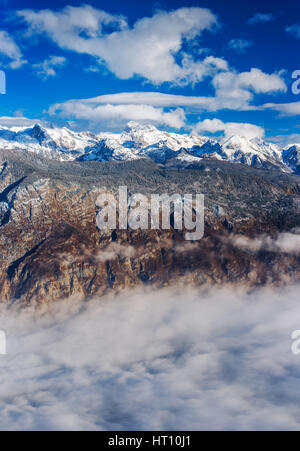 Super resolution impilati paesaggio del monte Triglav top in Slovenia sulla bella e soleggiata giornata invernale con soffici nuvole e nebbia sopra il lago di Bohinj Foto Stock