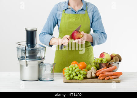 Anonimo donna che indossa un grembiule, pronto per iniziare a preparare un sano succo di frutta utilizzando moderne spremiagrumi elettrico, uno stile di vita sano concetto in backgr bianco Foto Stock