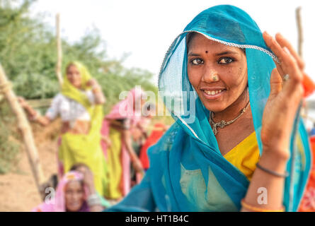 Una giovane e bella donna di Rajasthani in un blu brillante sari trattiene il suo velo di testa Foto Stock