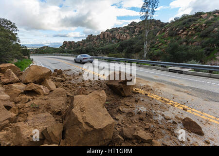 Los Angeles, California, Stati Uniti d'America - 18 Febbraio 2017: auto passando tempesta ha causato rock scorrere su Santa Susana Pass Road nella valle di San Fernando. Foto Stock