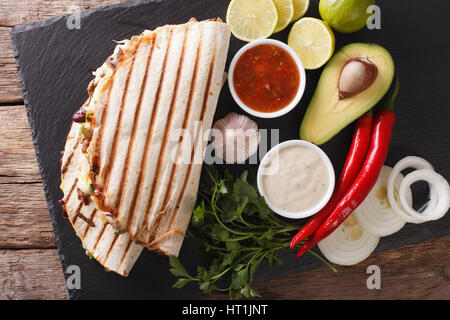 Mexican quesadilla con carne di manzo, fagioli, avocado e formaggio vicino sul tavolo. Vista orizzontale dal di sopra Foto Stock