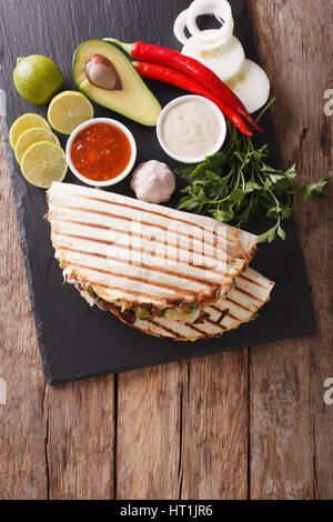 Mexican quesadilla con carne di manzo, fagioli, avocado e formaggio vicino sul tavolo. vista verticale da sopra Foto Stock