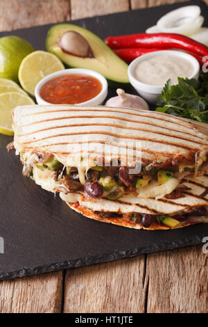 Quesadilla con carne di manzo, fagioli, avocado e formaggio vicino sul piano verticale. Foto Stock