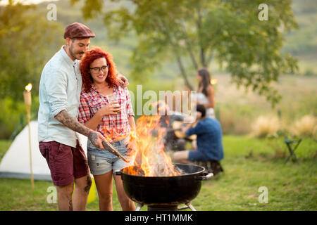 Coppia in amore di bere birra e preparare il grill fire in legno Foto Stock