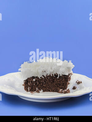 Un pezzo di torta al cioccolato con soffici glassa bianca guarnita con noce di cocco shreded su un bianco che serve la piastra. Oklahoma, Stati Uniti d'America. Foto Stock