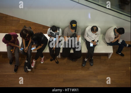 13.08.2016, Singapore, Repubblica di Singapore - Persone appoggiano su un banco a ION Orchard Shopping Mall. Foto Stock