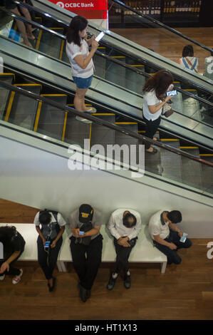13.08.2016, Singapore, Repubblica di Singapore - Persone appoggiano su un banco a ION Orchard Shopping Mall. Foto Stock