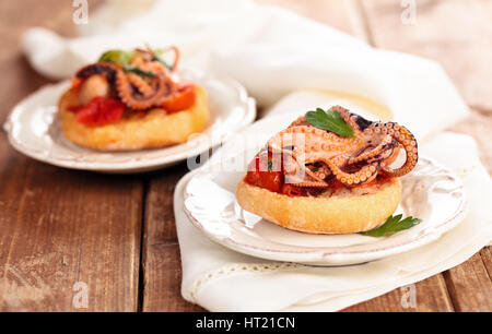 Il cibo italiano. Bruschetta con polipetti, pomodori e prezzemolo. Foto Stock