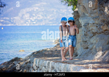 Due bambini, ragazzo fratelli, camminando su un percorso attorno a mare mediterranea sulla riviera francese, godendo assolato pomeriggio estivo Foto Stock