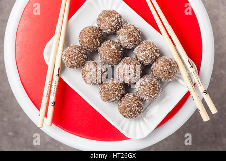 Morsi dolci fatti da dadi e date per vegan . In casa bar superfoods sani e bacchette cinesi e tè verde Foto Stock