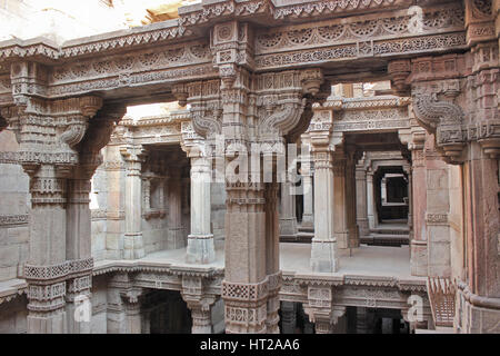 Piani superiori con intricati intarsi in pietra su pilastri, lesena e trabeazione. Adalaj Stepwell, Ahmedabad, Gujarat, India. Foto Stock