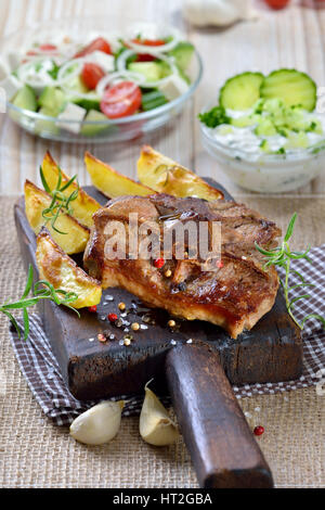 Pasto greco: fritto costolette di agnello con patate al forno cunei, agricoltori e insalata tzatziki Foto Stock