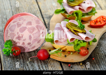 Rulli con fette di prosciutto, salsiccia e sottaceti servita su un rustico di legno Foto Stock