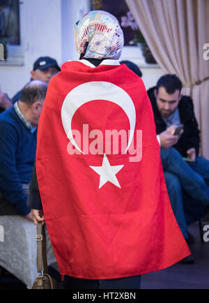 Kelsterbach, Germania. 06 Mar, 2017. Un sostenitore del presidente turco Recep Tayyip Erdogan e la sentenza la giustizia e lo sviluppo delle parti (AKP) partito indossa una bandiera turca durante una campagna di referendum in caso in cui il parlamentare AKP Taner Yildiz ha pronunciato un discorso a Kelsterbach, Germania, 06 marzo 2017. Diverse centinaia di sostenitori hanno partecipato all'evento. Foto: Boris Roessler/dpa/Alamy Live News Foto Stock