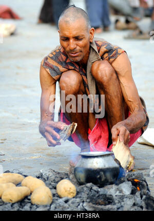 Un uomo cuoce pane sulla brace calda in Rajasthan Foto Stock