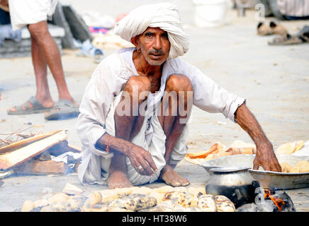 Un uomo cuoce pane sulla brace calda in Rajasthan Foto Stock