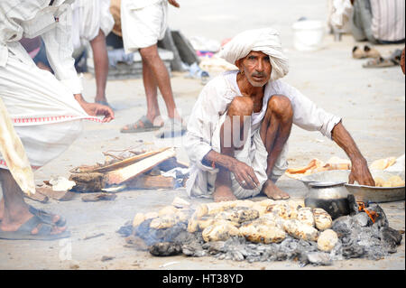 Un uomo cuoce pane sulla brace calda in Rajasthan Foto Stock