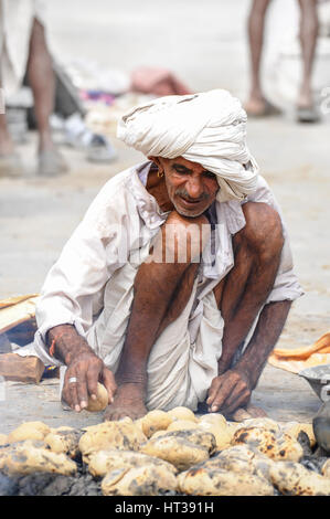 Un uomo cuoce pane sulla brace calda in Rajasthan Foto Stock