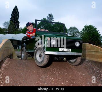 Bambino la guida un giocattolo di Land Rover. Artista: sconosciuto. Foto Stock