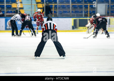 Vista posteriore sulla arbitro controlla la partita di hockey. Foto Stock