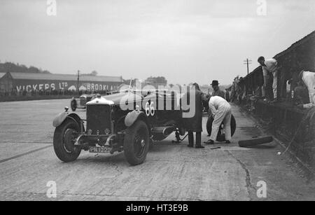 GL Baker's 5954 cc Minerva subendo una ruota posteriore cambiare a Brooklands. Artista: Bill Brunell. Foto Stock