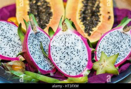 La sezione trasversale del drago di frutta o pitahaya con sullo sfondo la sezione trasversale di una papaia Foto Stock