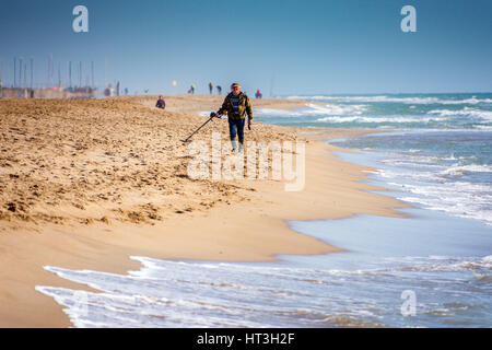 L'uomo con il rivelatore di metalli sulla spiaggia Foto Stock