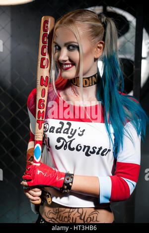 Ritratto di ragazza sorridente in costume Harley Quinn. Essa si erge con un  bat. Lei è vicino a griglia. Close up. Cosplay Foto stock - Alamy