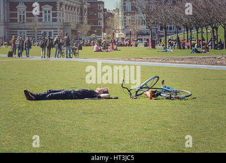 Aprile 10, 2015 persone agghiacciante al sole sulla Museumplein in Amsterdam, sullo sfondo la Concertgebouw. Foto Stock