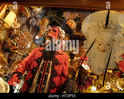 Maschere del Carnevale di Venezia esposte in una vetrina durante la vivace celebrazione in Italia Foto Stock