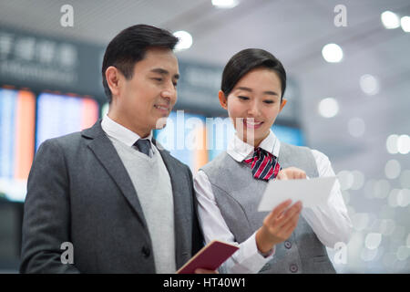 Sorridenti hostess della compagnia aerea e il passeggero Foto Stock