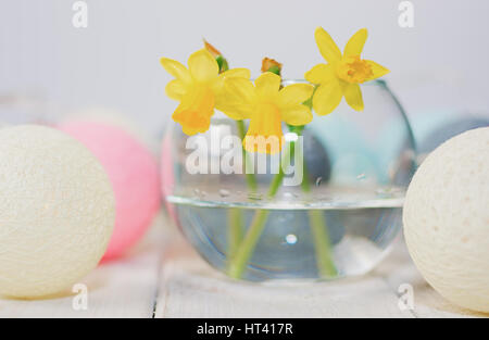 Giunchiglie in un vaso circondato da round lampade in forma di palline colorate su di un tavolo di legno. Foto Stock