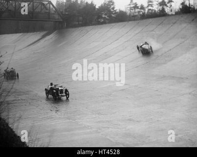 Austin 7 e la filatura Riley di HL Roberts, BARC montagna corsa, Brooklands, Surrey, 1931 Artista: Bill Brunell. Foto Stock