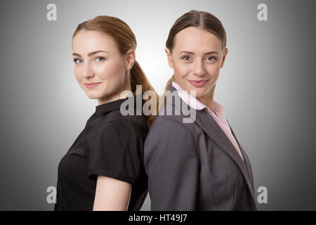 Due modelli di business in piedi con le loro spalle insieme. Isolato su bianco Foto Stock