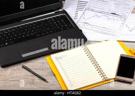 Aprire il notebook, occhiali, computer, penna e smartphone su un tavolo di legno. Close-up Foto Stock