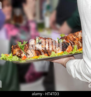 La mano del cameriere dando un piatto di carne presso il ristorante Foto Stock