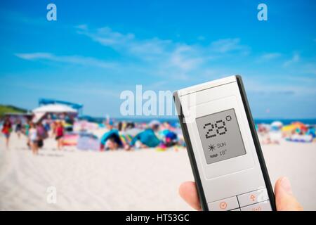 Mano azienda termometro elettronico. La gente sulla spiaggia in background Foto Stock