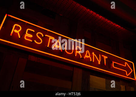 Ristorante Litted firmare con la freccia fatta di rosso luce fluorescente nella parete con sfondo scuro Foto Stock