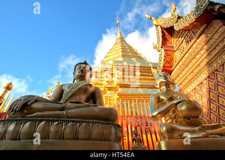 Statue di Buddha e la pagoda dorata contro il cielo blu e chiaro al Wat Phra That Doi Suthep, un famoso Theravada tempio buddista a Chiang Mai, Thailandia Foto Stock