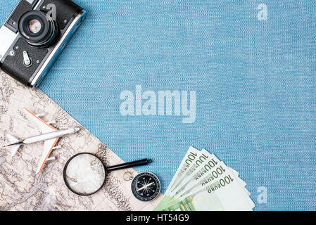 Preparazione per il concetto di viaggio, guarda, aereo, denaro, passaporto, matite, prenota, auricolare, Photo frame, occhiaie su sfondo blu con spazio di copia Foto Stock