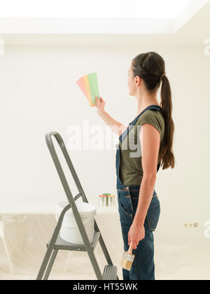 Vista posteriore di bruna guardando dipingere i campioni di colore per il suo appartamento Foto Stock