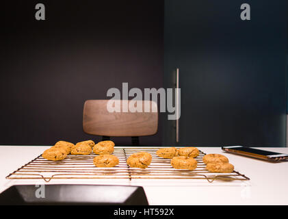 La cottura in un grigio scuro cucina murata, con ciambelle sul raffreddamento per rack Foto Stock
