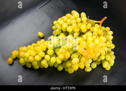 Uve di grandi dimensioni cluster di colore giallo su sfondo nero Foto Stock