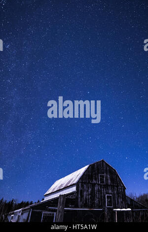 Rural Log Cabin fienile di notte con le stelle e la via lattea e la neve e gli alberi su una farm di Ontario Foto Stock