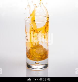 Splash in bicchiere di scotch whisky con cubetti di ghiaccio Foto Stock