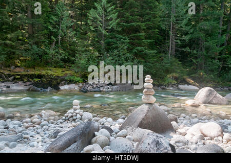 Pietre impilate su una grande roccia su un fiume nella foresta Foto Stock