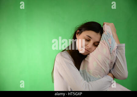 Una ragazza in un nightgown appoggiato contro il cuscino su una verde chroma key sullo sfondo Foto Stock